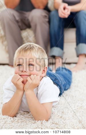 Lindo niño acostado en el piso y viendo la televisión con sus padres