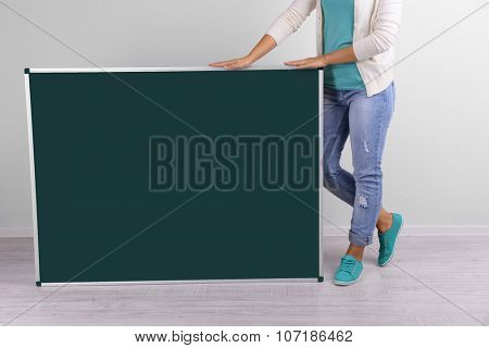 Woman in causal with green blackboard on grey background, close up