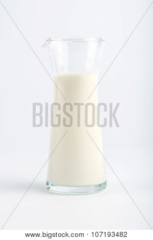 Fresh milk in a glass jug on a white background.