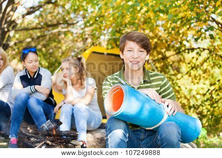 Happy boy holds blue rolled spandex mat sitting