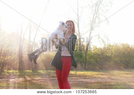 Happy Young Mother Plays With Her Little Daugther At Sunny Autumn Day