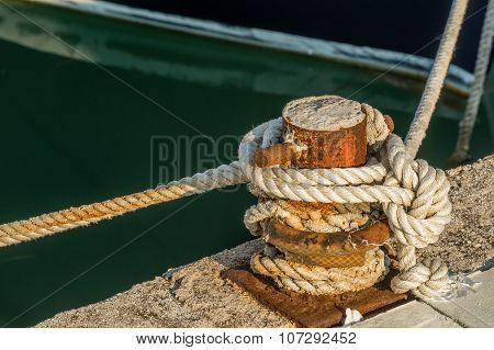 Ship rope tightly bound to the rusty quay.