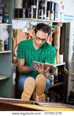 Relaxed worker using tablet computer while sitting in paper factory