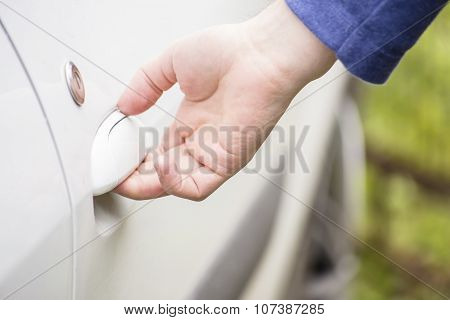 Man Opens The Door Of A White Car Outdoors