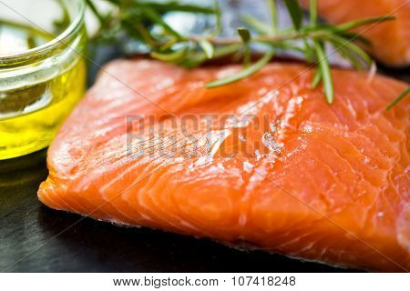 Portions Of Fresh Raw Salmon Fillets With Aromatic Herbs And Olive Oil