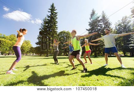 fitness, sport, friendship and healthy lifestyle concept - group of happy teenage friends exercising and doing squats at boot camp