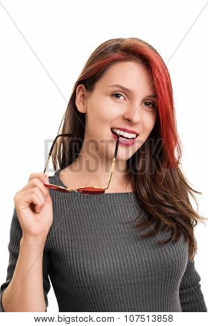 Close up portrait of a smiling beautiful young woman biting the shackle of glasses, looking at the camera, isolated on white background. Beautiful smiling girl with a shackle of glasses in her mouth.