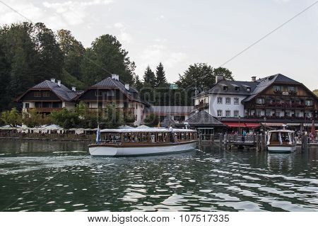 KOENIGSSEE, GERMANY - AUGUST 13, 2015: Pleasure boat at the landing stage of Schoenau where the boat trips on the Koenigsseet start historic buildings are in the background