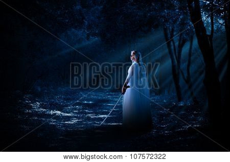 Young elven girl with sword in night forest