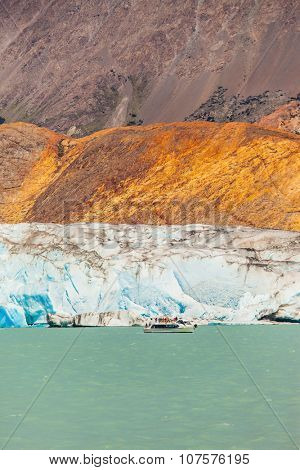 Unique lake Viedma in Patagonia. The enormous glacier sliding into the lake. From the edge of the glacier break off huge blue floes. Pleasure tourist boat floats to the glacier