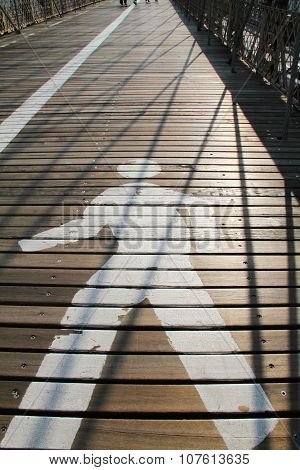 Pathway sign on Brooklyn Bridge with morning sunlight and shadow from cable lines