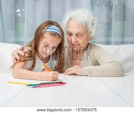portrait of little girl with grandmother drawing with pencils