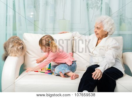grandmother and granddaugter with cat on white sofa