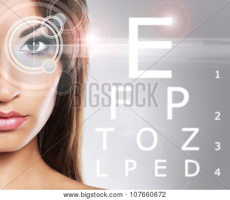 Beautiful woman with eye scanning over grey background.