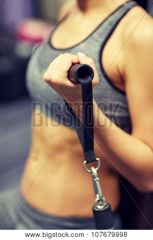 sport, fitness, lifestyle and people concept - close up of young woman flexing muscles on cable gym machine