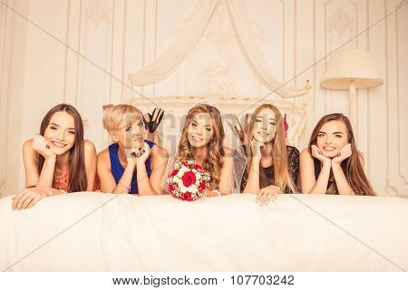 Cheerful Girls Celebrating A Bachelorette Party Of Bride Liying On The Bed