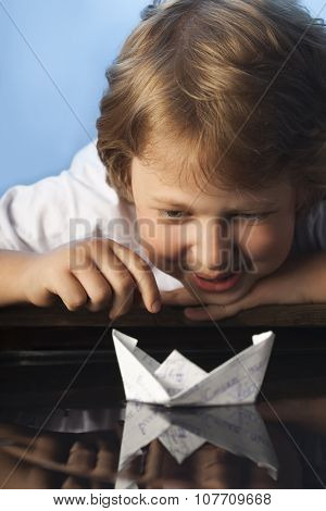 boy play in paper ship in water puddel