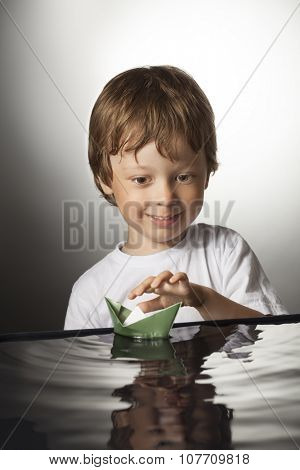 boy play in paper ship in water puddel