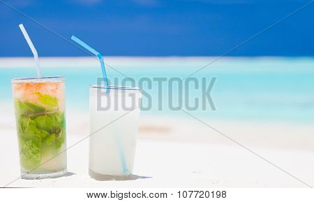 exotic mojito and pina colada cocktails on white sand beach