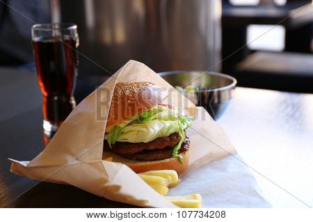 Sandwich and french fried potatoes in craft paper on a table