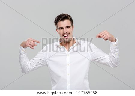 Smiling handsome successful happy confident man in white shirt pointing on himself