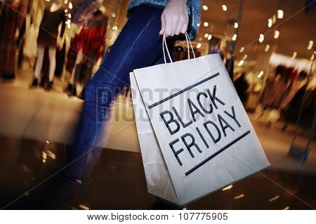 Modern shopper with Black Friday paperbag going in the mall