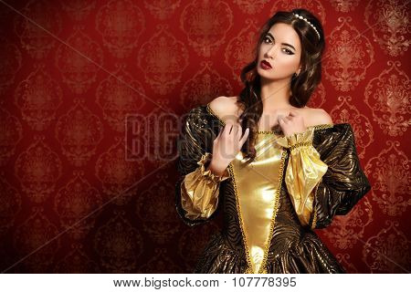 Beautiful young lady in the lush expensive dress posing over vintage background. Renaissance. Barocco. Fashion.