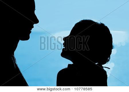 Мать с дочерью сидеть на берегу, напротив друг друга смехом