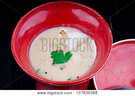 Vegetable soup served in a red cup on a black wooden table