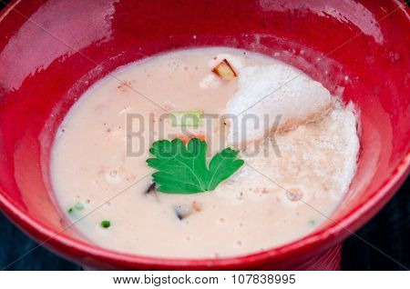 Vegetable potage served in a red cup on a black wooden table