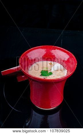 Vegetable soup served in a red cup on a black wooden table