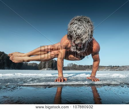 Man doing yoga exercise (parsva bakasana) on the ice of frozen lake
