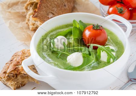 Arugula and tomatoes puree soup in white bowl