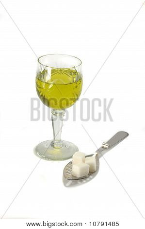 Copa de vino con absenta y cuchara con azúcar piezas - todavía vida sobre fondo blanco