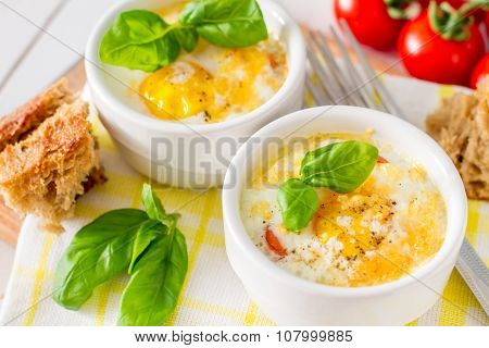 Egg cocotte  in white ramekin with tomato and basil
