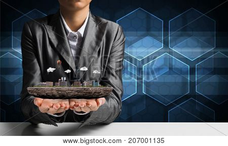 Cropped image of businessman in suit presenting in his hands modern city block with media icons on background. 3D rendering.
