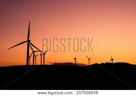 Wind turbines at a wind farm reflected on a water surface at sunset, Crete, Greece