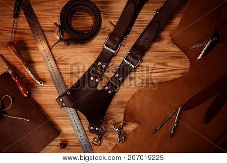 Leather craft and belt for photographers. Tanner's tools on grey wooden background top view.