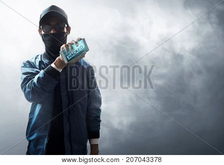Unknown hacker holding mobile phone on smoke background