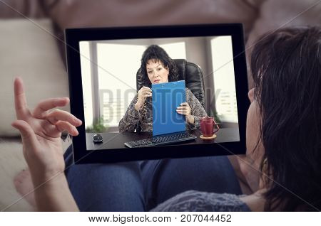 Woman sitting on couch receives virtual mental health care by telemedicine app installed on digital tablet