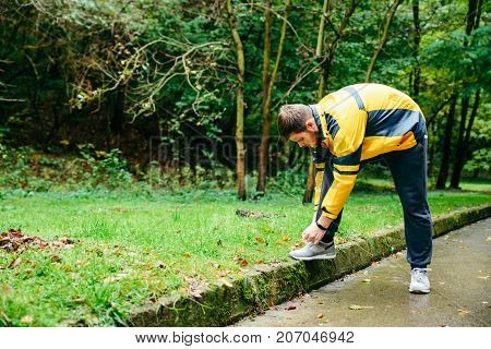 Running and sport concept.Sportsman hands tying shoelaces. autumn rainy day