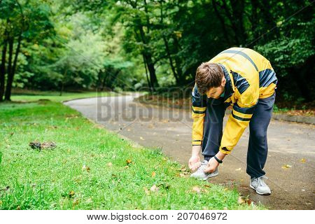 Running and sport concept.Sportsman hands tying shoelaces. autumn rainy day