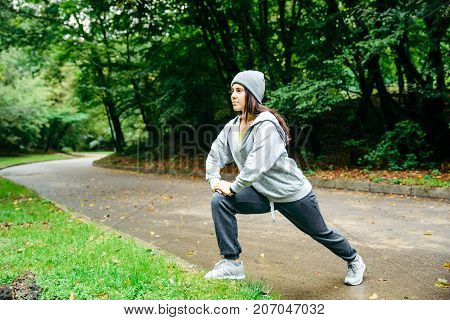 woman stretching in city park in autumn day