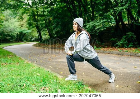 woman stretching in city park in autumn day