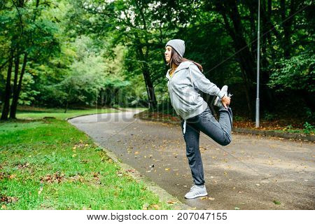 woman stretching in city park in autumn day