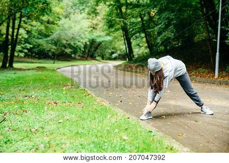 woman stretching in city park in autumn day