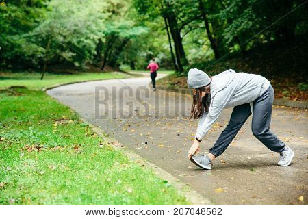 woman stretching in city park in autumn day