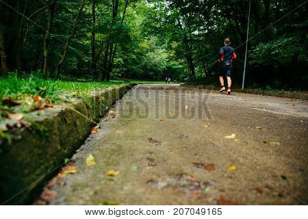 man runnin in autumn park with music in rainy weather
