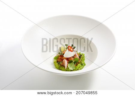 Menu in Pan-Asian cuisine - Tartar from salmon with avocado cream cheese chili pepper and fresh greens in the white bowl