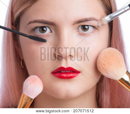 Beautiful young woman with makeup brushes around face
